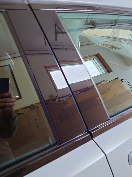 Högblanka listerna på en bildörr efter polering, reflekterar omgivningen tydligt och ser släta ut.