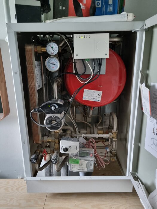 Värmesystem med pump, manometrar och kablar, moderniserat från ECL 100 till ECL 120, med nyligen ordnade kablar inuti en skåpinstallation.