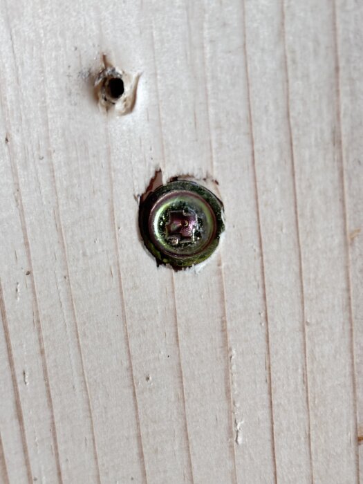 Kuvassa on ruuvi puupinnalla, jossa on epätavallinen, laaja profiili.