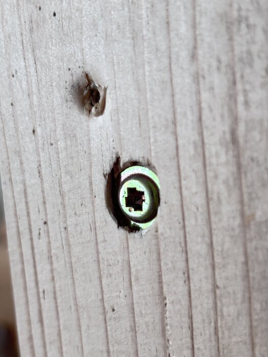 Ruuvin pää, jossa on tuntematon uraprofiili, upotettuna puuhun.