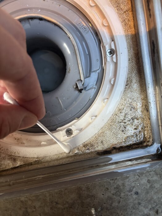 Sprickor i tätskiktet runt en golvbrunn i badrum, pekas ut med tops, visar potentiella skador eller läckageproblem.