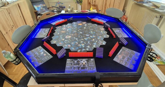 Brädspel med hexagonbräde och färgglada barriärer på ett bord med blå belysning, redo för spelhelg.
