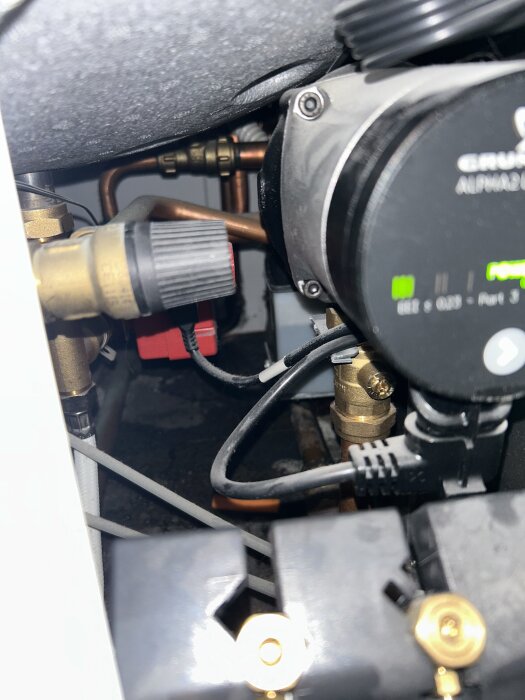 Säkerhetsventil och rörledningar med anslutningar i närbild, samt en elektrisk komponent bredvid.