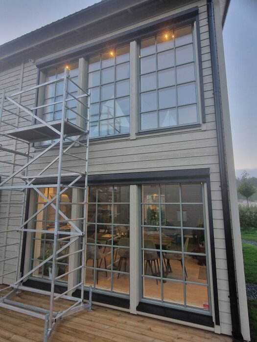 Stort glasfönster och dörr installerade på husfasad med byggställning bredvid.