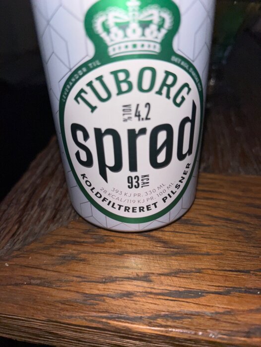 Burk med Tuborg Spred pilsner, 4.2% vol, stående på ett träbord.