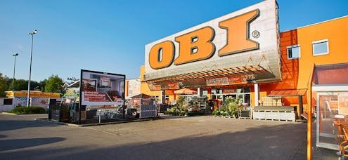 OBI Markt-byggvaruhus i Bayern med orange fasad och stora OBI-skyltar, parkeringsplats i förgrunden.