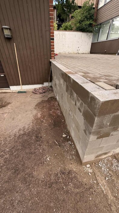 Murad uteplats med betongklossar och kant som oroar för halka. Borste och slang syns vid sidan.