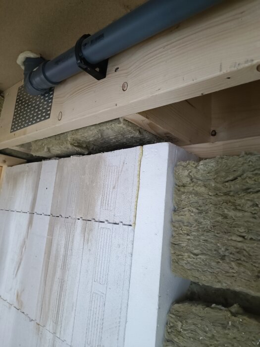 Byggnad med thermomur, rör ovanför, och isolering på sidorna i en källare under konstruktion.