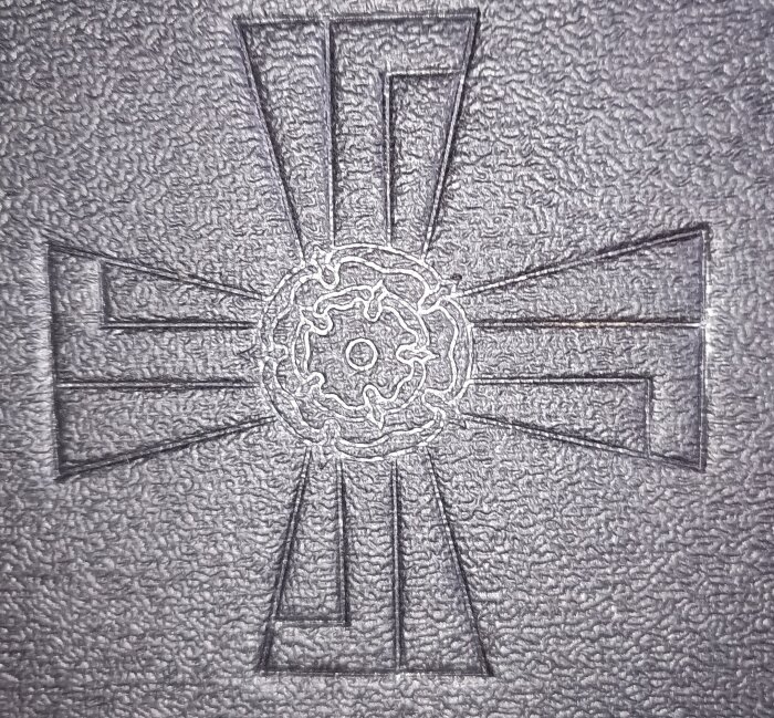 Inristat mönster av ett Georgskors med centralt rosettliknande motiv, tidigare logotyp för finska flygvapnet från 1918.