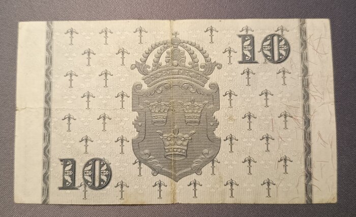 Gammal svensk tiokronorssedel med krona och tre kronor motiv.