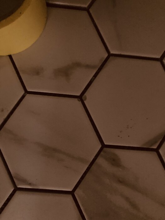 Hexagonala golvplattor i mosaik med några skadade bitar.