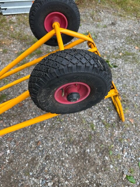 Gul kärra upp och ner med två svarta slanglösa hjul; ett projekt med däcktätning pågår. Grusig bakgrund.