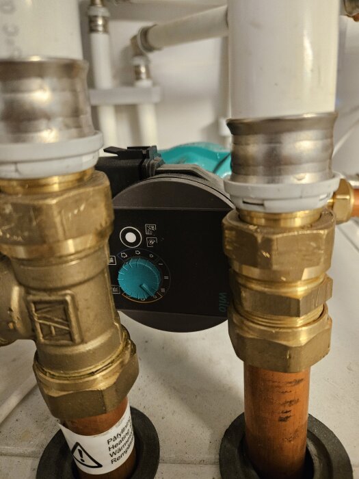 Värmesystem med kopparrör och ventiler, tryckregulator synlig i mitten.