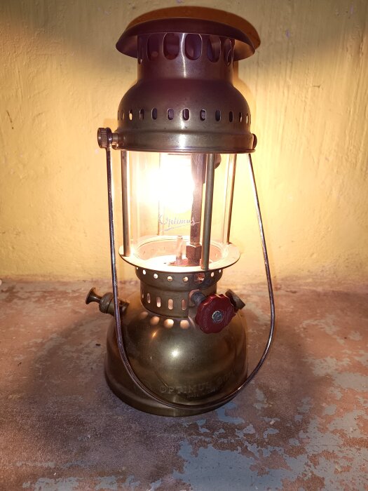 Gammal Optimuslykta av mässing i drift, med starkt sken mot ljus bakgrund.