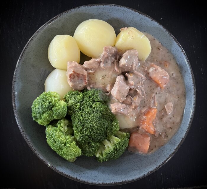 Tallrik med dillkött och dillsås, serverat med kokt potatis och broccoli.