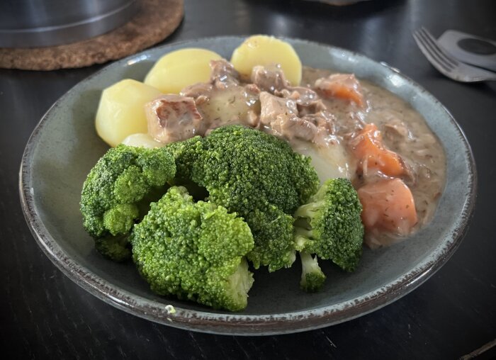 Dillkött med dillsås serverat med kokt potatis och broccoli på en tallrik.