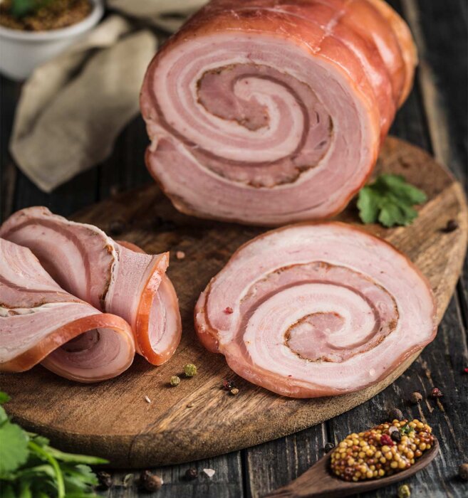 Rullad köttbit med inslag av fett på en skärbräda, tillsammans med små skålar av senap och kryddor.