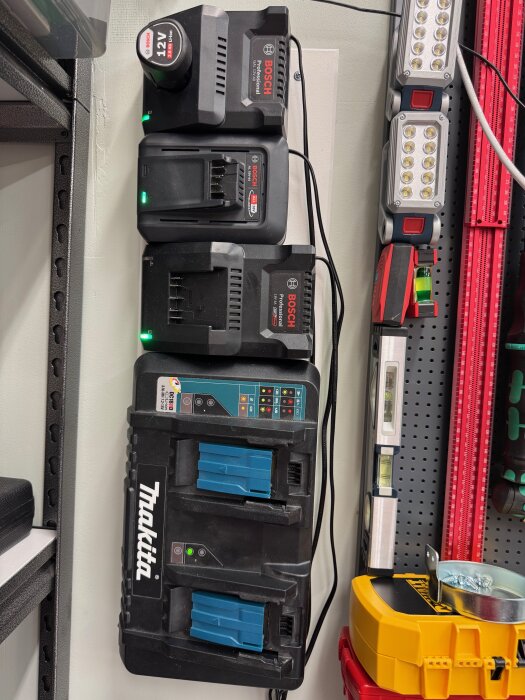 Batteriladdare från Bosch och Makita samt verktygsvägg med vattenpass och handverktyg.