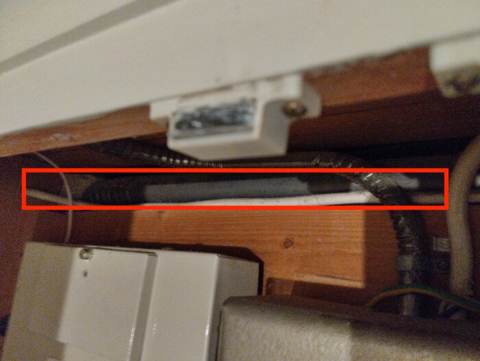 Elcentral med olika kablar och pansarrör för elinstallation. Ett grått pansarrör löper horisontellt med rött markeringsfokus, tjänar grannen.