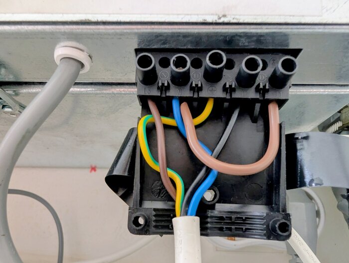 Anslutna elledningar i en kopplingsplint, med fokus på jordledningar och nollans förbindelse i förhållande till en kondensor.