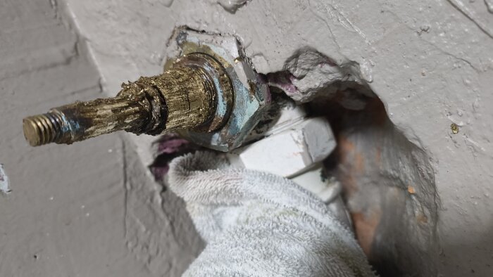 Trasigt slottsvred delvis omgivet av murbruk, nära en vit trasa. Inget händer när man vrider insatsen.