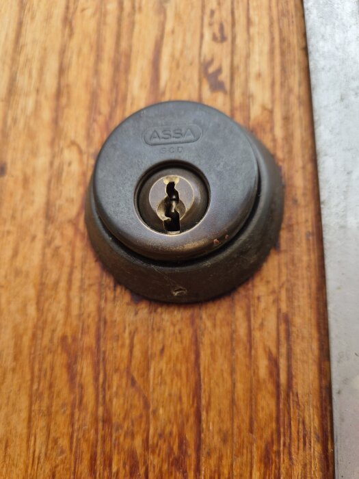 Närbild av ett Assa dörrlås monterat på en brun träyta.