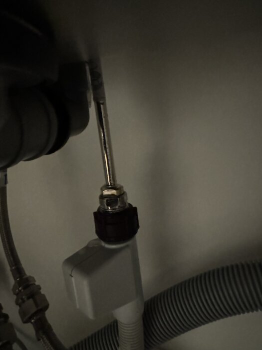 Vattenläcka vid rörkopplingen under diskbänken, nära blandaren. Synligt är metallrör och plastkopplingar.