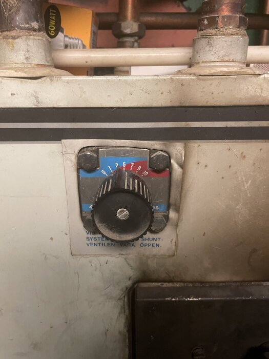 Reglage och tryckmätare på en äldre kombinationspanna, märkt med termometernummer och blå/röd skala, omgiven av rör och ledningar.