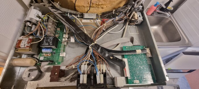 Öppen panel av en Nibe värmepump, med synliga kretskort, kablar och komponenter. Kablarna anslutna till temperaturbegränsaren är delvis smälta.