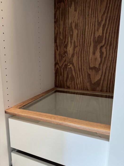 Egendesignad garderobsinredning med glashyllor och trädetaljer av furu, inom en vit garderob.