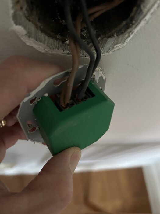 Grön dimmer med kablar synliga, delvis borttagen från väggen, ommålad så modellen är svår att identifiera.