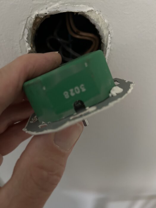 Grön dimmer utanpå vägg, övermålad, tas bort för identifiering. Siffrorna "3028" synliga. Ansluten till kablar i väggen.