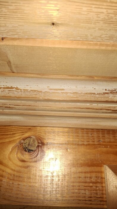 Missfärgningar på träpanel i bastu, med fläckar av vitaktig ton och träets naturliga ådringar synliga.