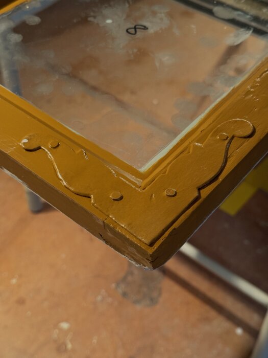 Gammalt hörnjärn målat i guldockra linoljefärg. Glaset är delvis målat och ska rengöras med rakbladsskrapa.