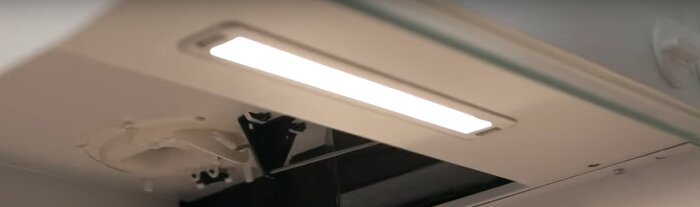 Invändig vy av spiskåpa med synliga spjällkopplingar och belysning.