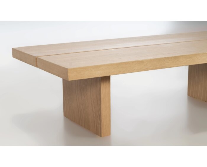 Ett soffbord med enkel design i ljust trä, med en slät bordsskiva uppdelad i tre sektioner och stadiga, raka ben.