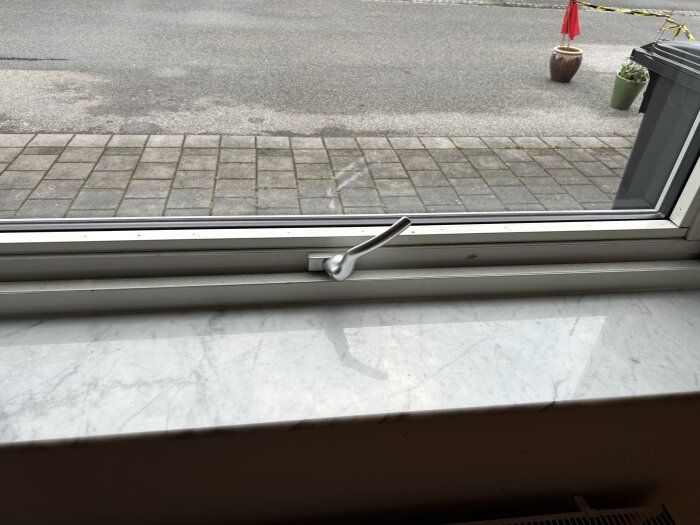 Spanjolettlås på ett fönster med problem att stänga, handtaget är placerat vid sidan nertill.