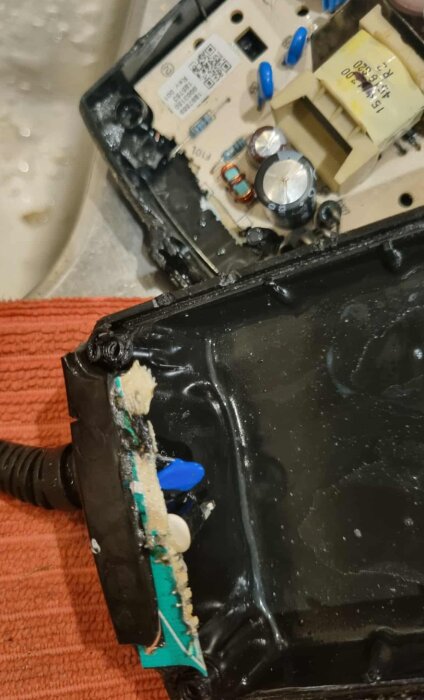 Transformator med smält del och blottade kretsar, synlig skada och komponenter, del av ett byggprojektproblem.