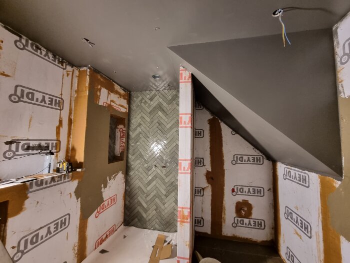 Renovering av dusch med fiskbensmönstrade kakel på vägg.