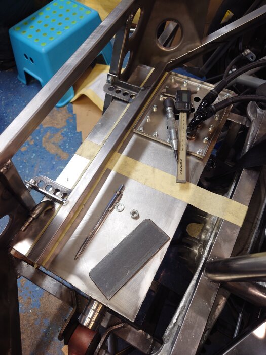 Metallkonstruktion i bagageutrymme med monterad tank och verktyg på golvet, del av byggprojekt.