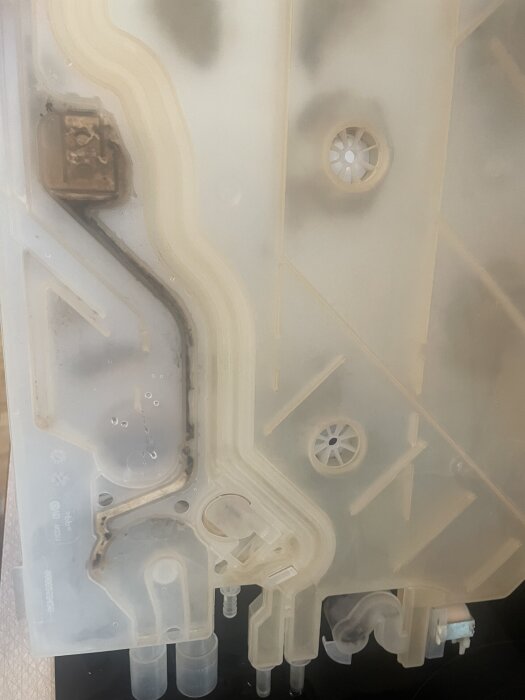 Plasttank med små kanaler för avloppssystem, delvis igensatta av fett. Tanken innehåller funktioner för tryckutjämning vid utpumpning.