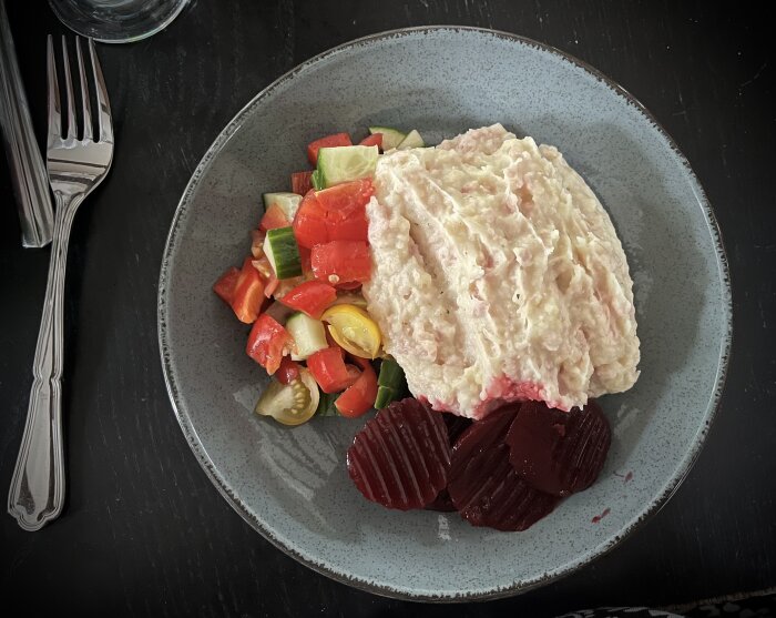 Tallrik med lapskojs av burkskinka, kokt potatis, serverad med skivade rödbetor och en färgglad grönsaksblandning.