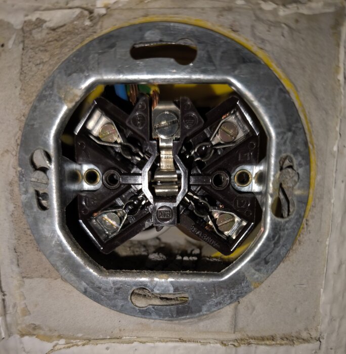 Eluttag med synliga skruvanslutningar och en blå ledare i övre vänstra skruven.