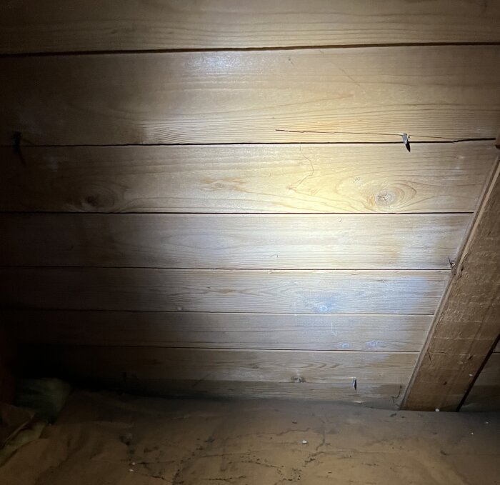 Vindens trätak med några synliga springor, belyst av en ficklampa.