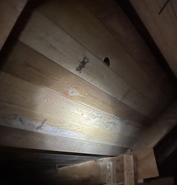 Vind med trätak och isolering, misstänkta mögelfläckar syns. Bilden är tagen för att kontrollera fukt och röta.