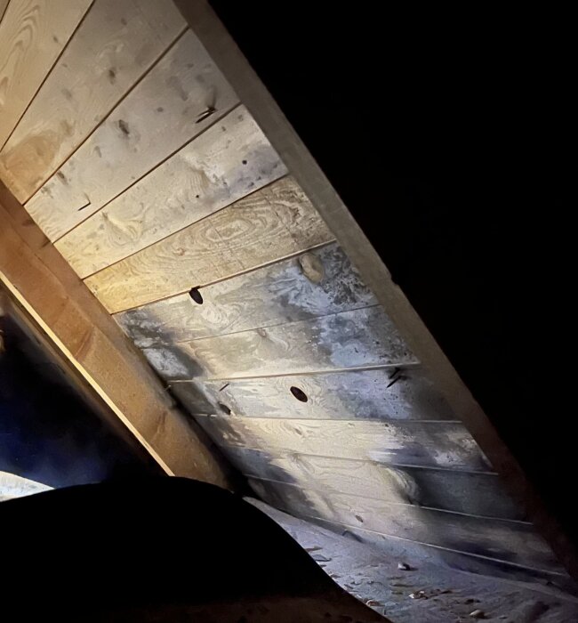 Vindsyll med tecken på fukt och möjlig rötskada, fotograferad med potentiella hål och missfärgningar som syns på brädorna.