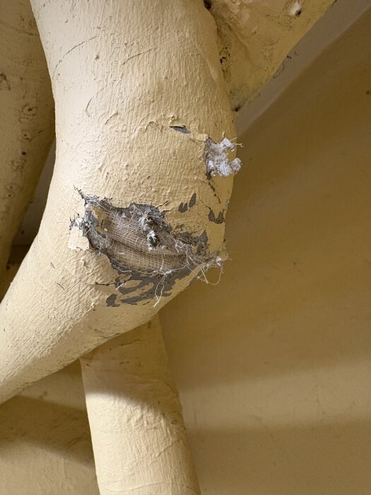 Rör i källare med sliten färg och synlig isolering, potentiellt asbestmaterial från tidigt 1900-tal.