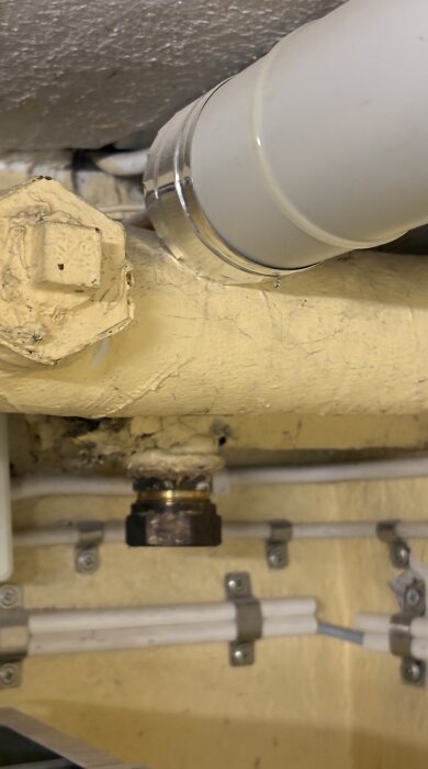 Gula, slitna rör med synlig isolering i källare från tidigt 1900-tal, potentiella asbestrisker diskuterade.