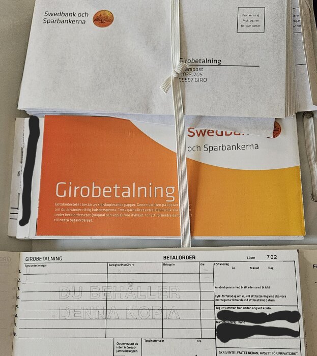 Girobetalningsblanketter från Swedbank staplade och hopsatta med snöre.