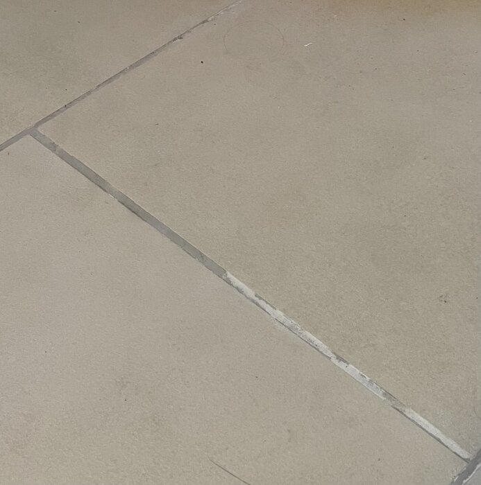 Färgen på fogarna i nyrenoverat badrumsgolv är ojämn med synliga skiftningar nära duschen, inkluderar vita nyanser på bild.